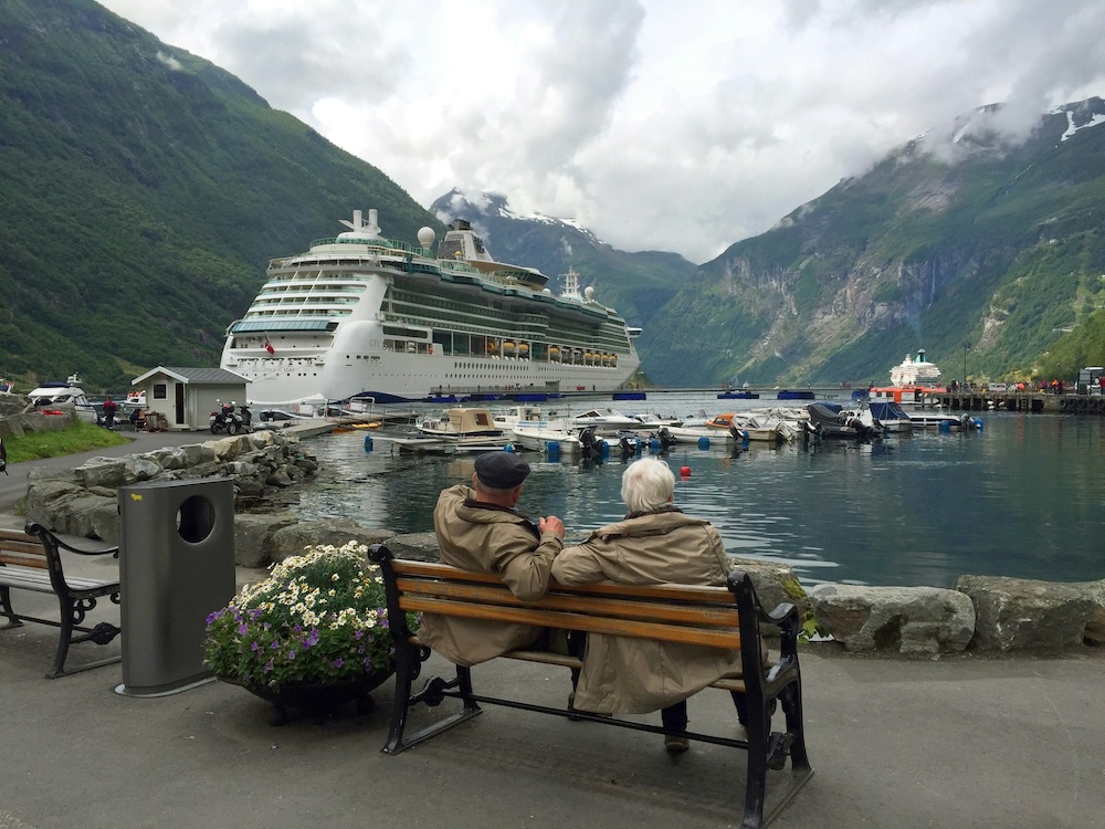 Elderly couple enjoying cruise vacation by scenic mountains